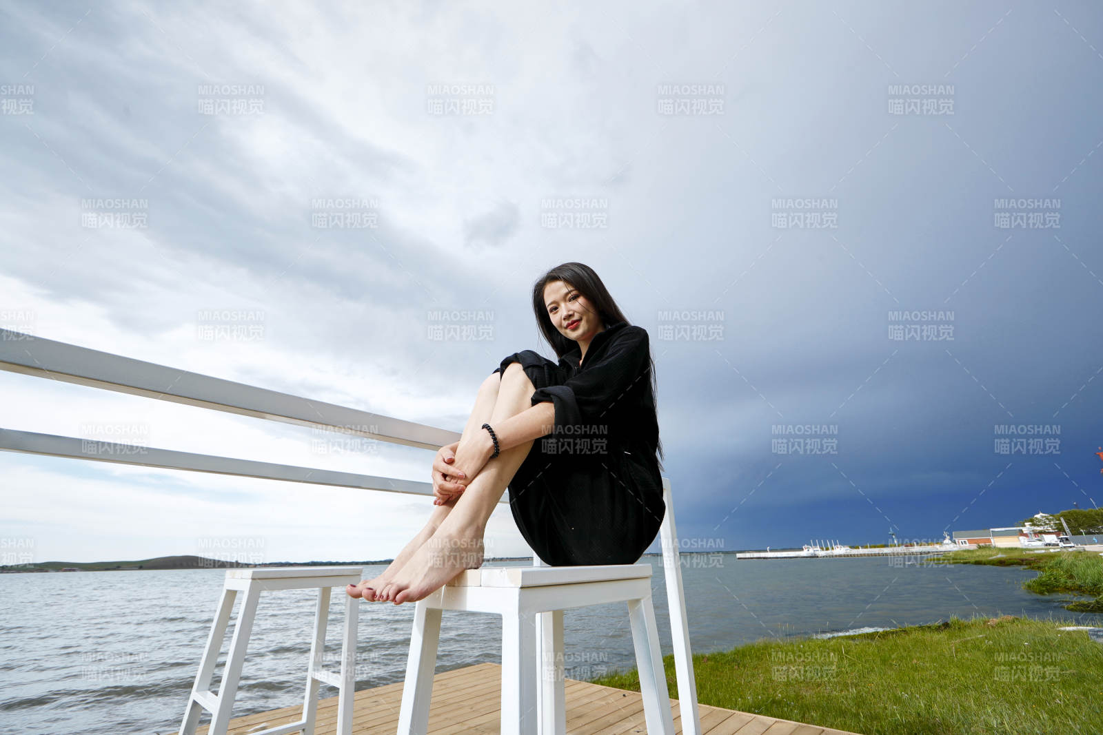 悠闲的坐在美丽湖岸码头的长发少女