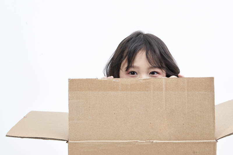 躲在纸箱中玩耍的调皮可爱亚洲小女孩儿童