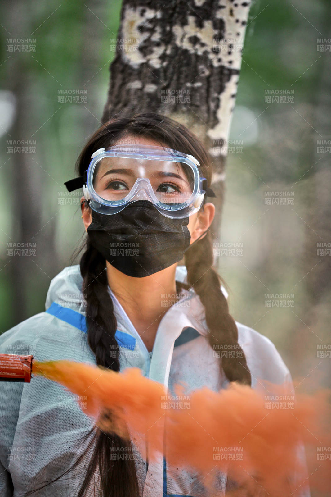 手执彩烟身穿防护服装的女性医疗人员