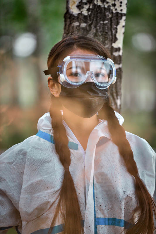 手执彩烟身穿防护服装的女性医疗人员