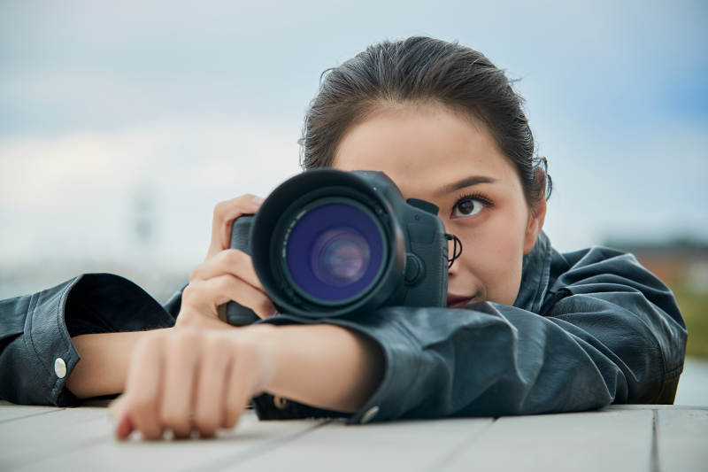 户外湖畔进行拍摄的亚洲青年女性摄影师