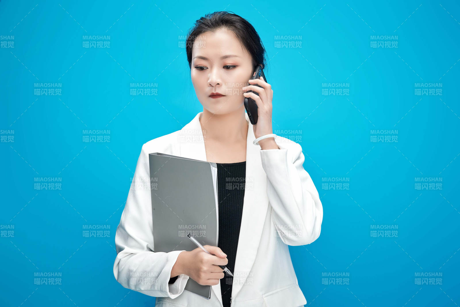 身穿西服拿着手机与文件夹的亚洲商务女士