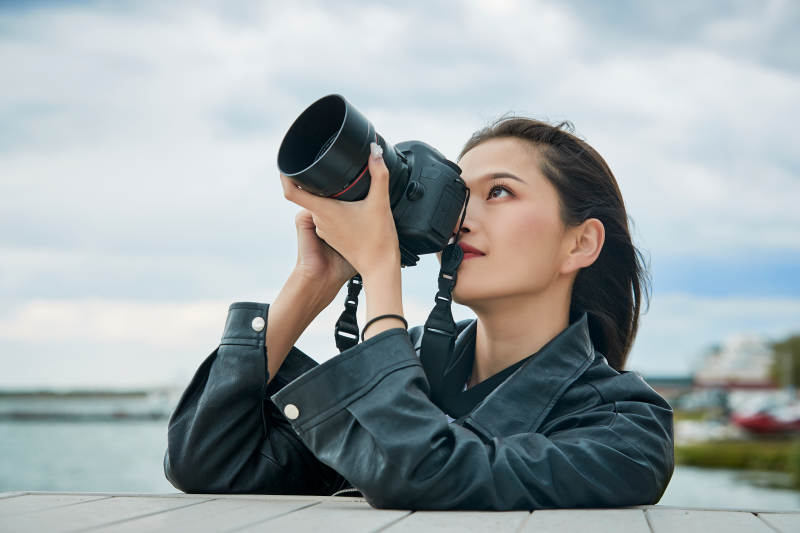 户外湖畔进行拍摄的亚洲青年女性摄影师