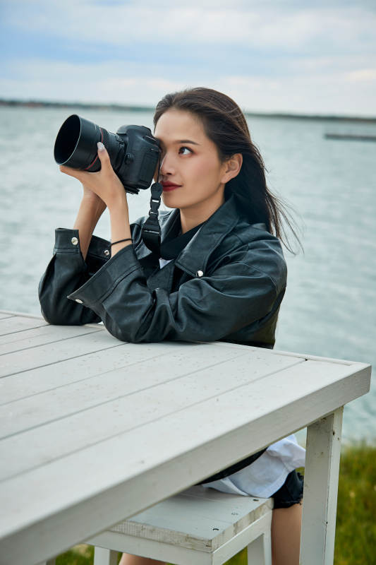 户外湖畔进行拍摄的亚洲青年女性摄影师