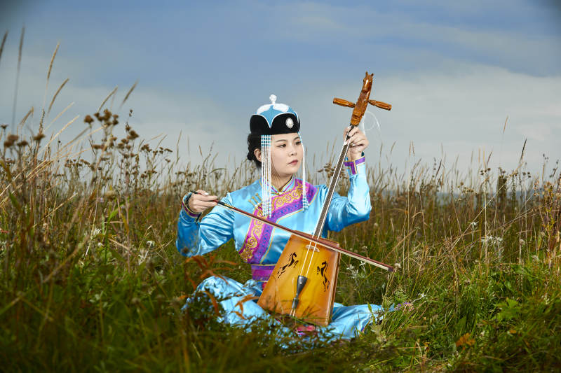 草原上穿蒙古族服饰拉马头琴的蒙族女乐手