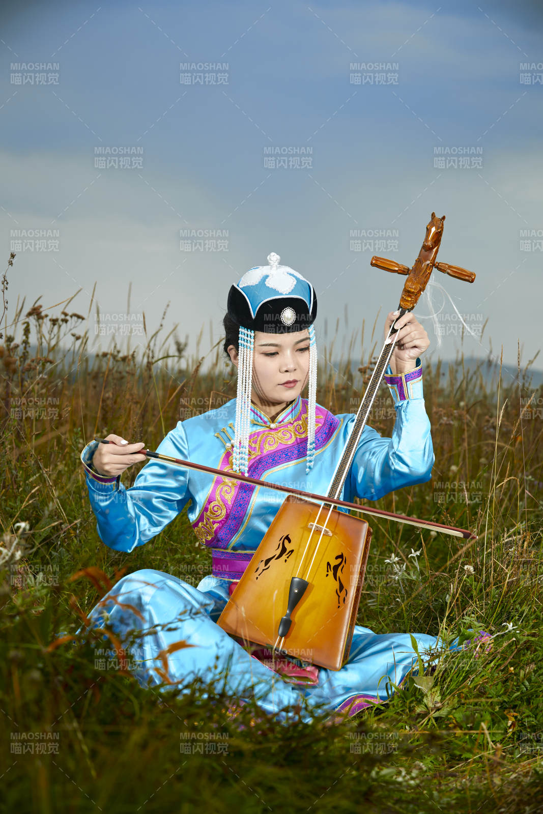 草原上穿蒙古族服飾拉馬頭琴的蒙族女樂手