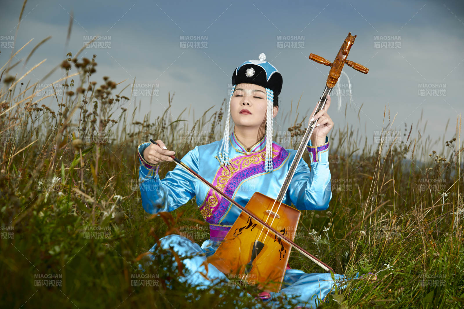 草原上穿蒙古族服飾拉馬頭琴的蒙族女樂手