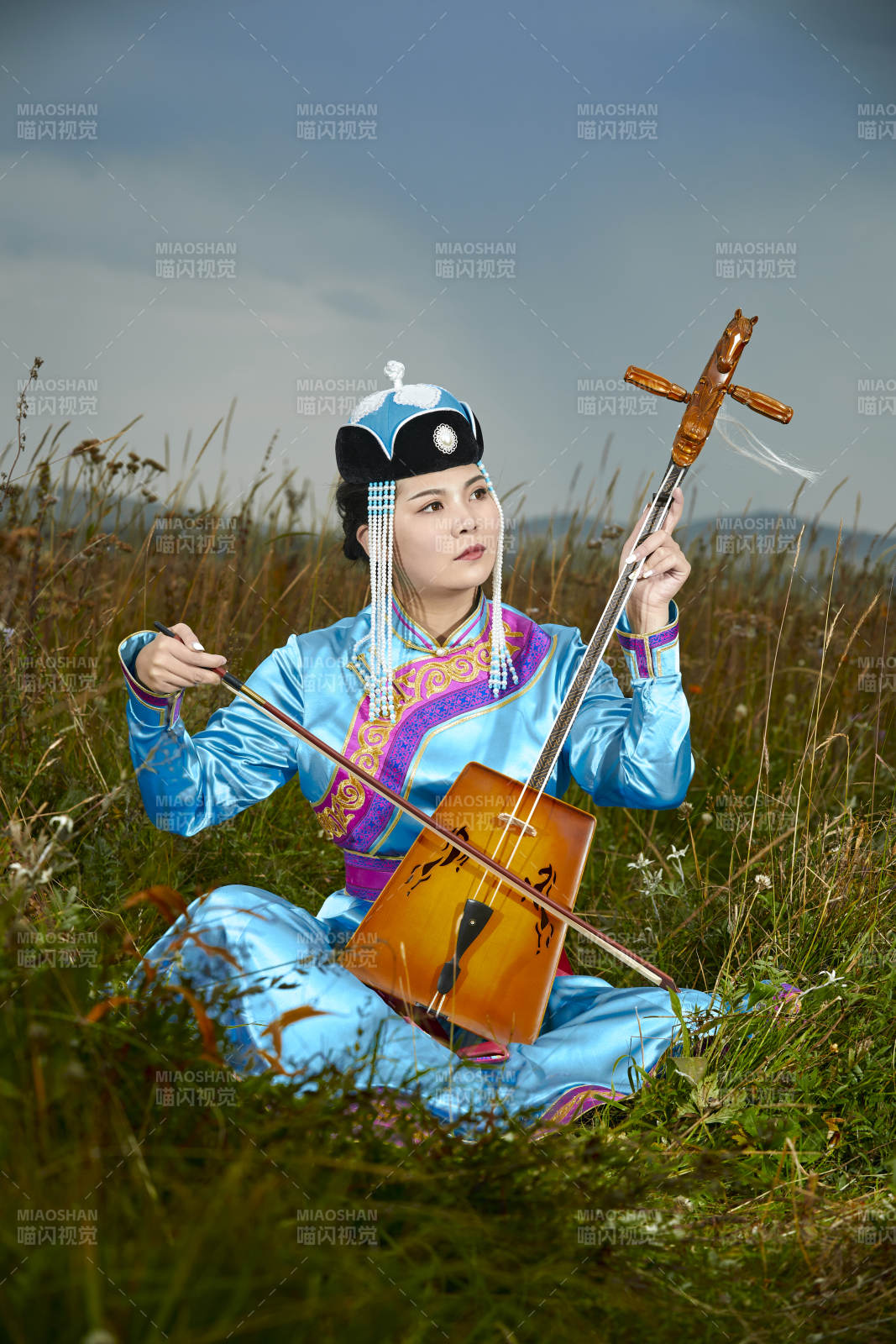 草原上穿蒙古族服飾拉馬頭琴的蒙族女樂手