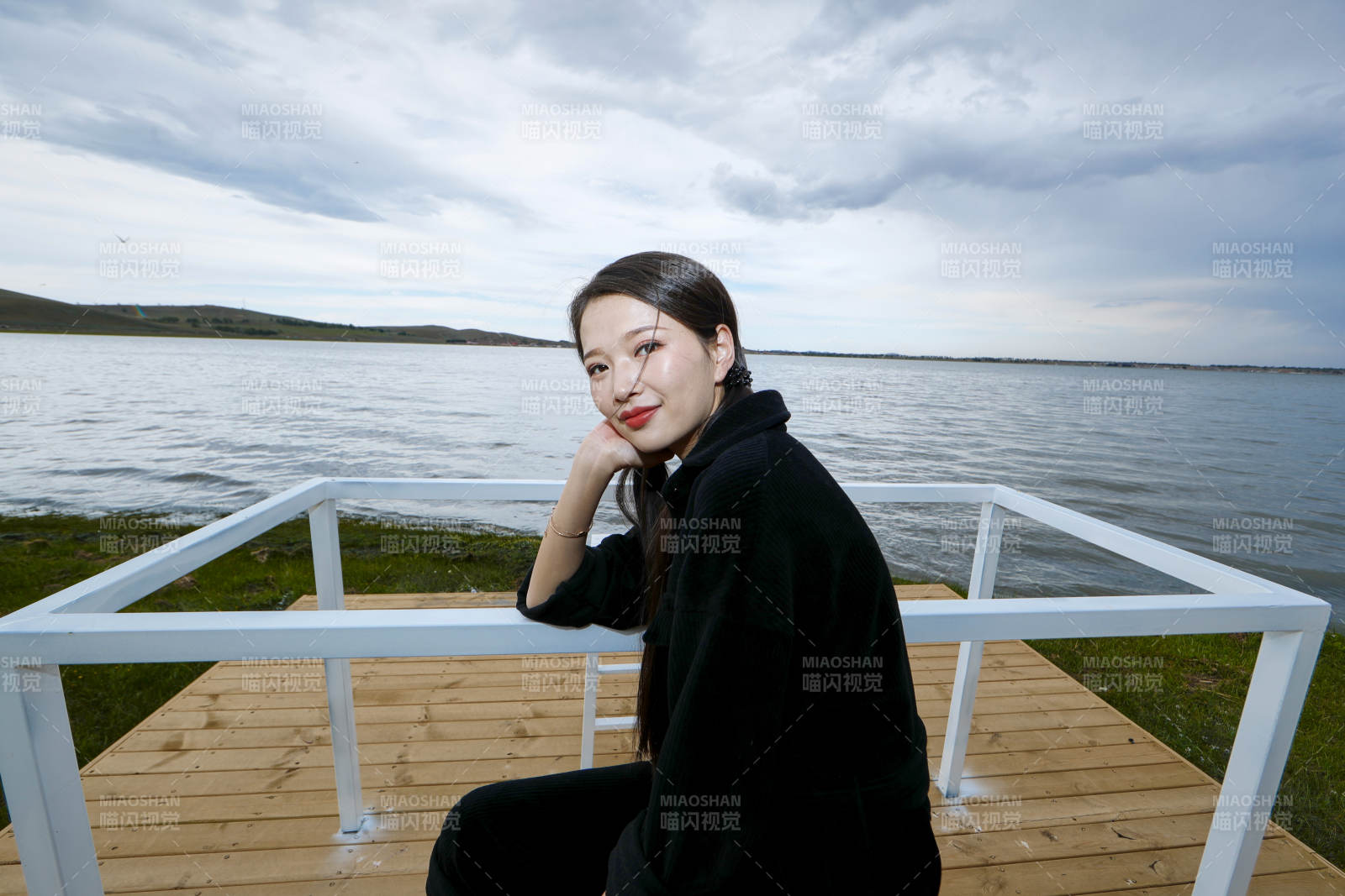 悠閑的坐在美麗湖岸碼頭的長發(fā)少女