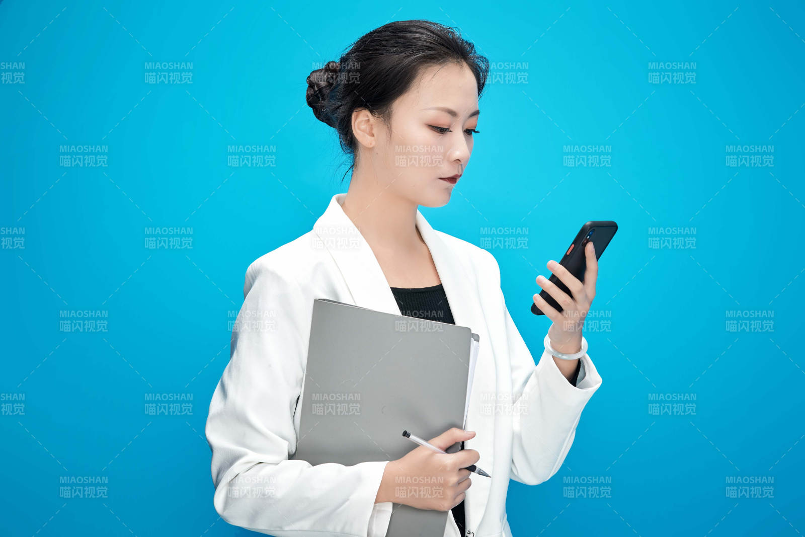 身穿西服拿著手機(jī)與文件夾的亞洲商務(wù)女士