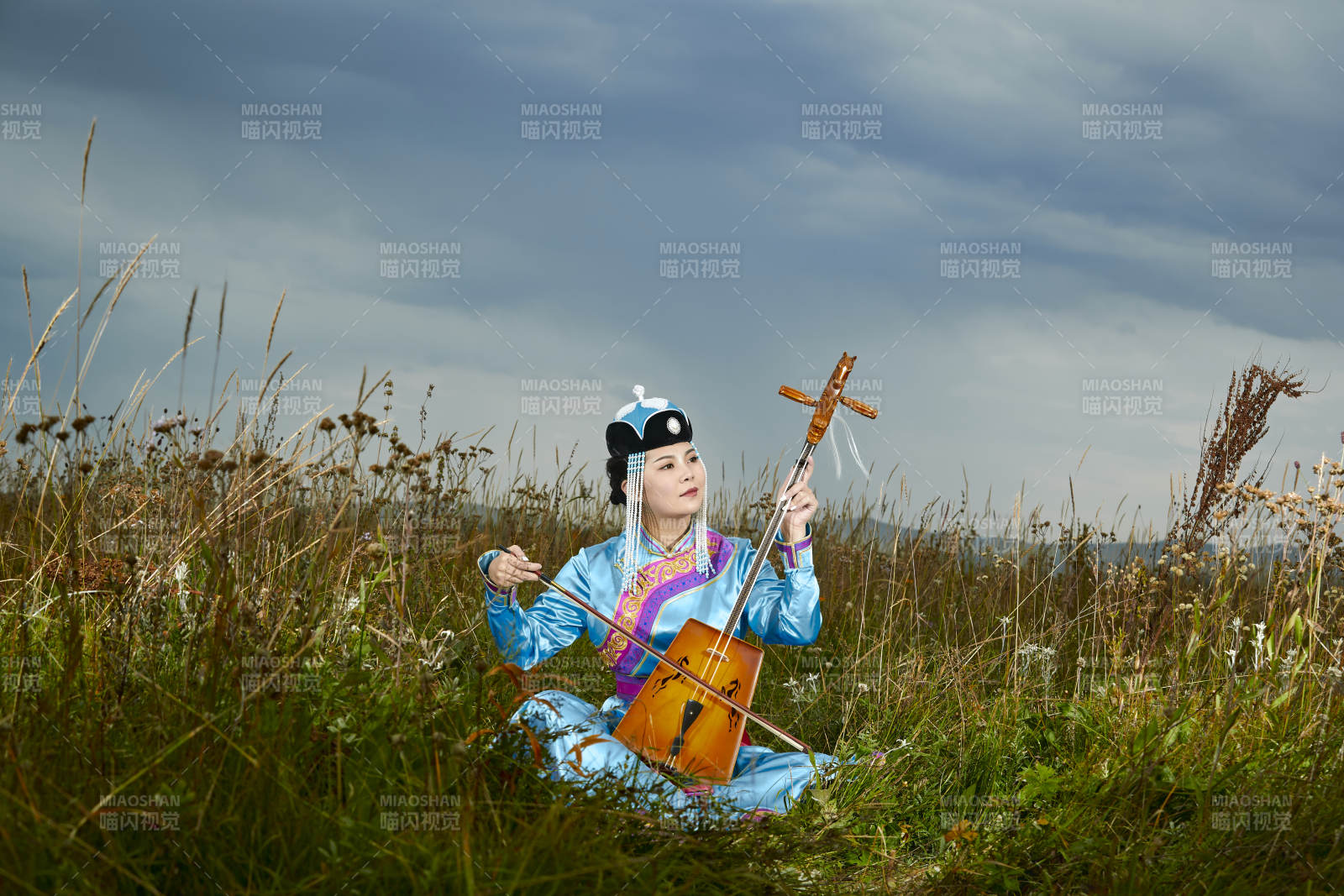 草原上穿蒙古族服飾拉馬頭琴的蒙族女樂手