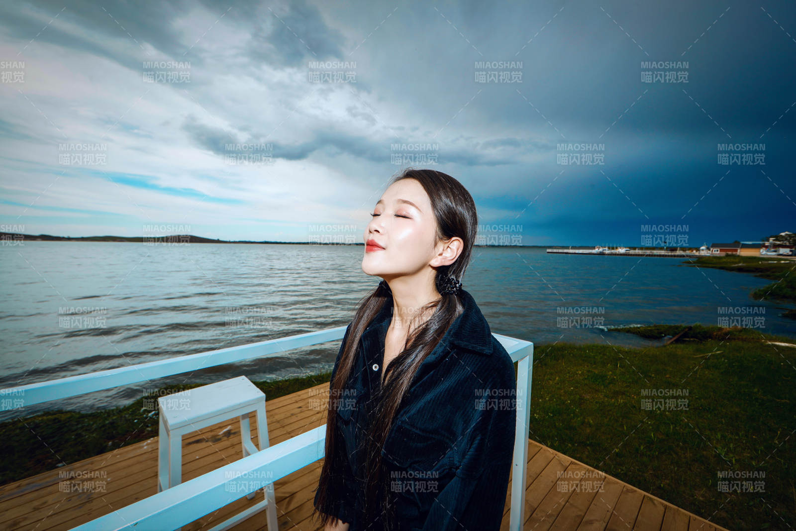 悠闲的坐在美丽湖岸码头的长发少女