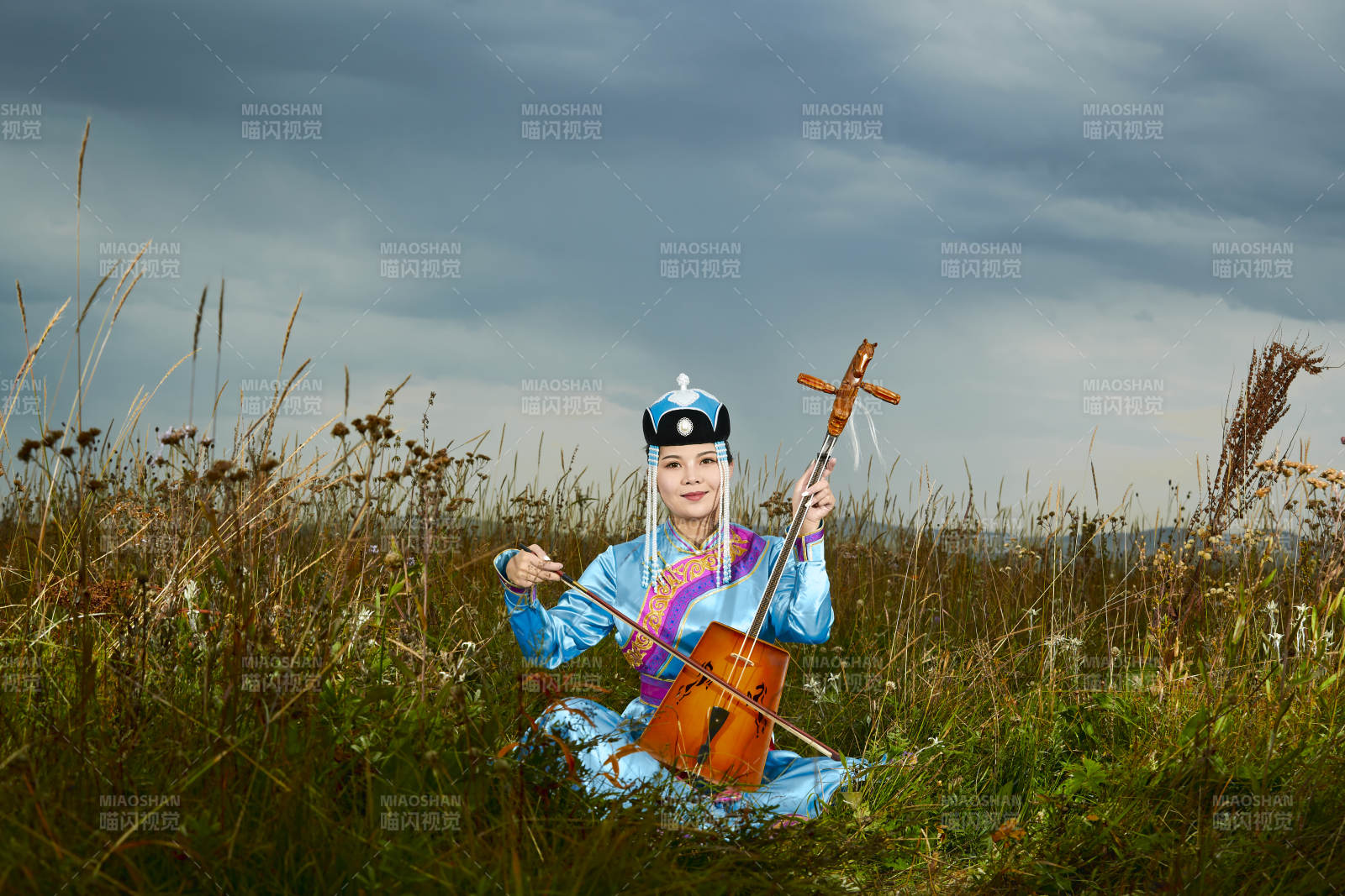 草原上穿蒙古族服飾拉馬頭琴的蒙族女樂手
