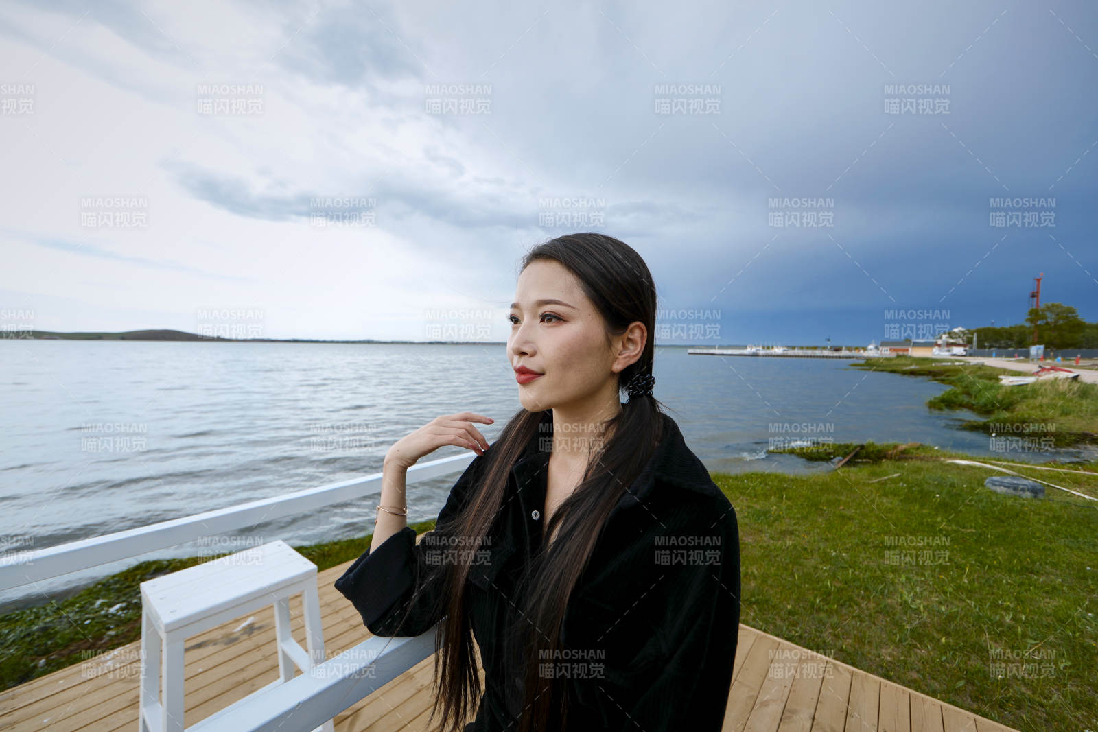 悠閑的坐在美麗湖岸碼頭的長發少女