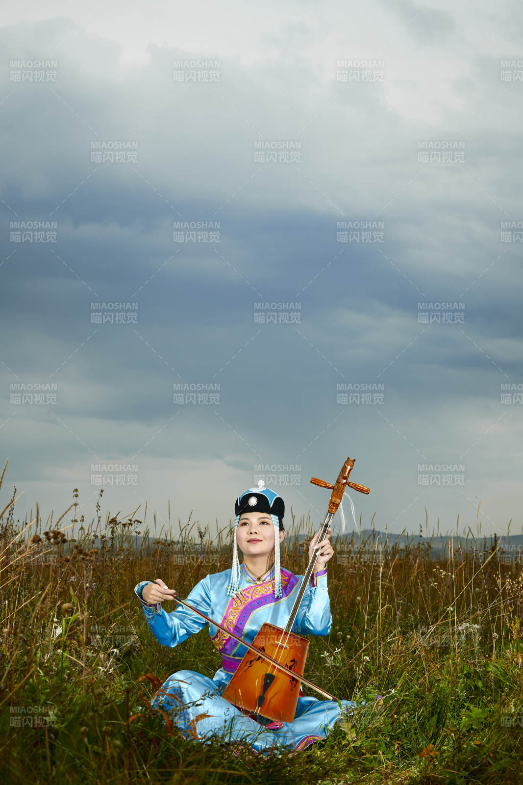 草原上穿蒙古族服飾拉馬頭琴的蒙族女樂手