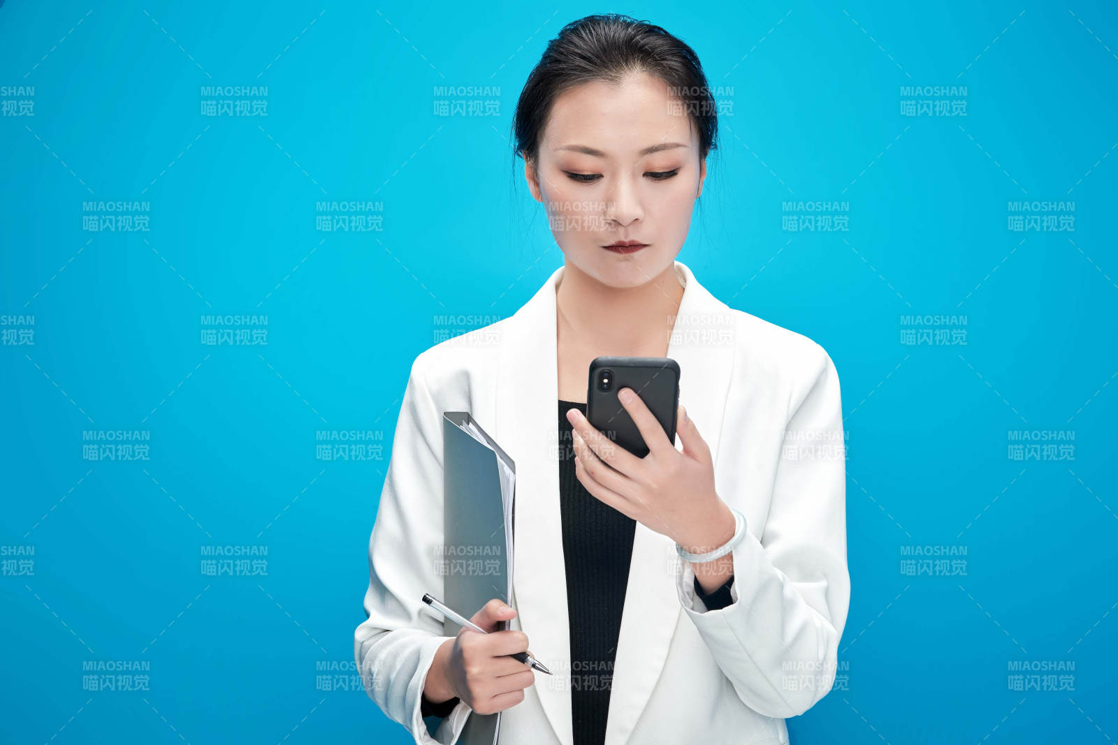 身穿西服拿著手機與文件夾的亞洲商務(wù)女士