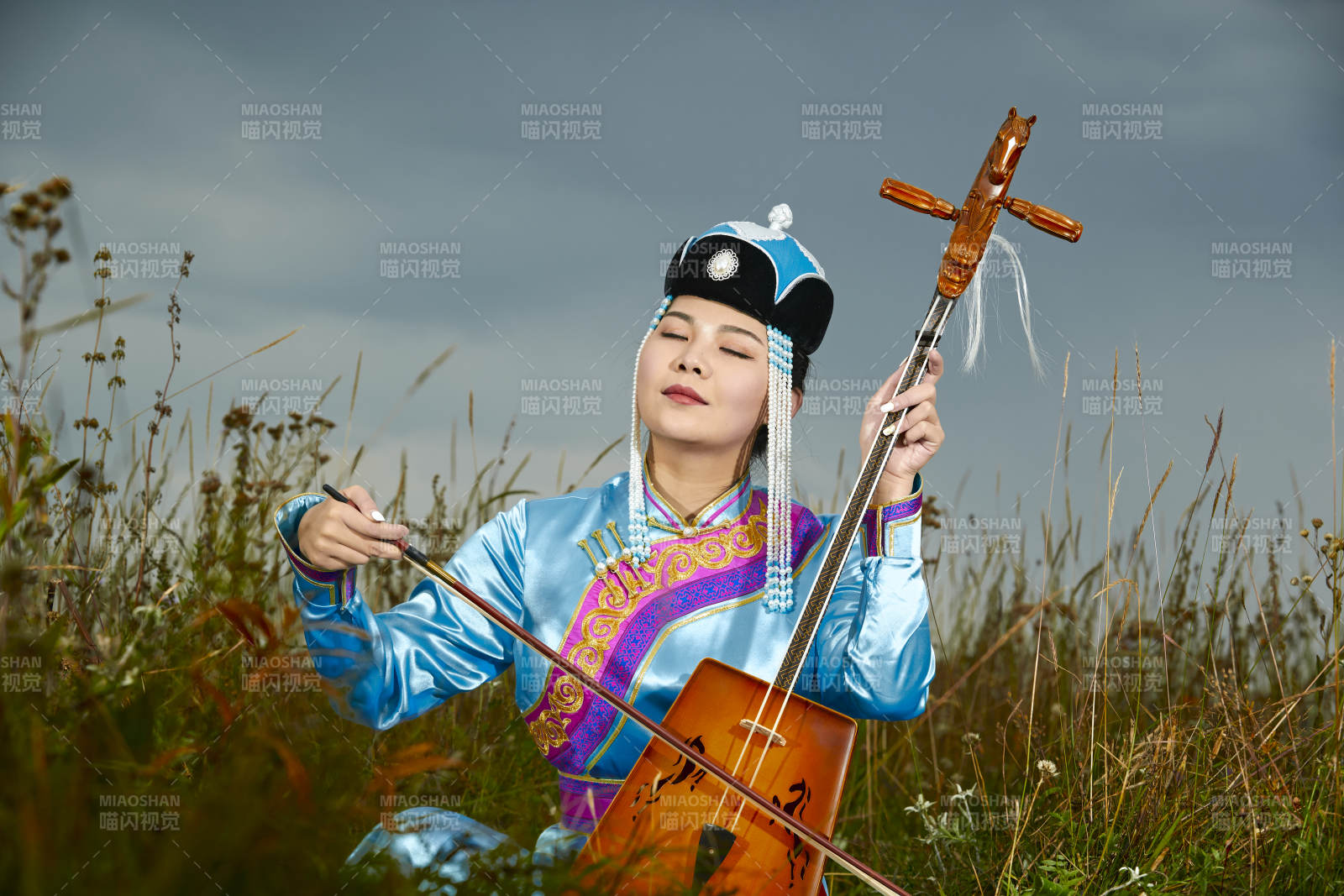 草原上穿蒙古族服飾拉馬頭琴的蒙族女樂手