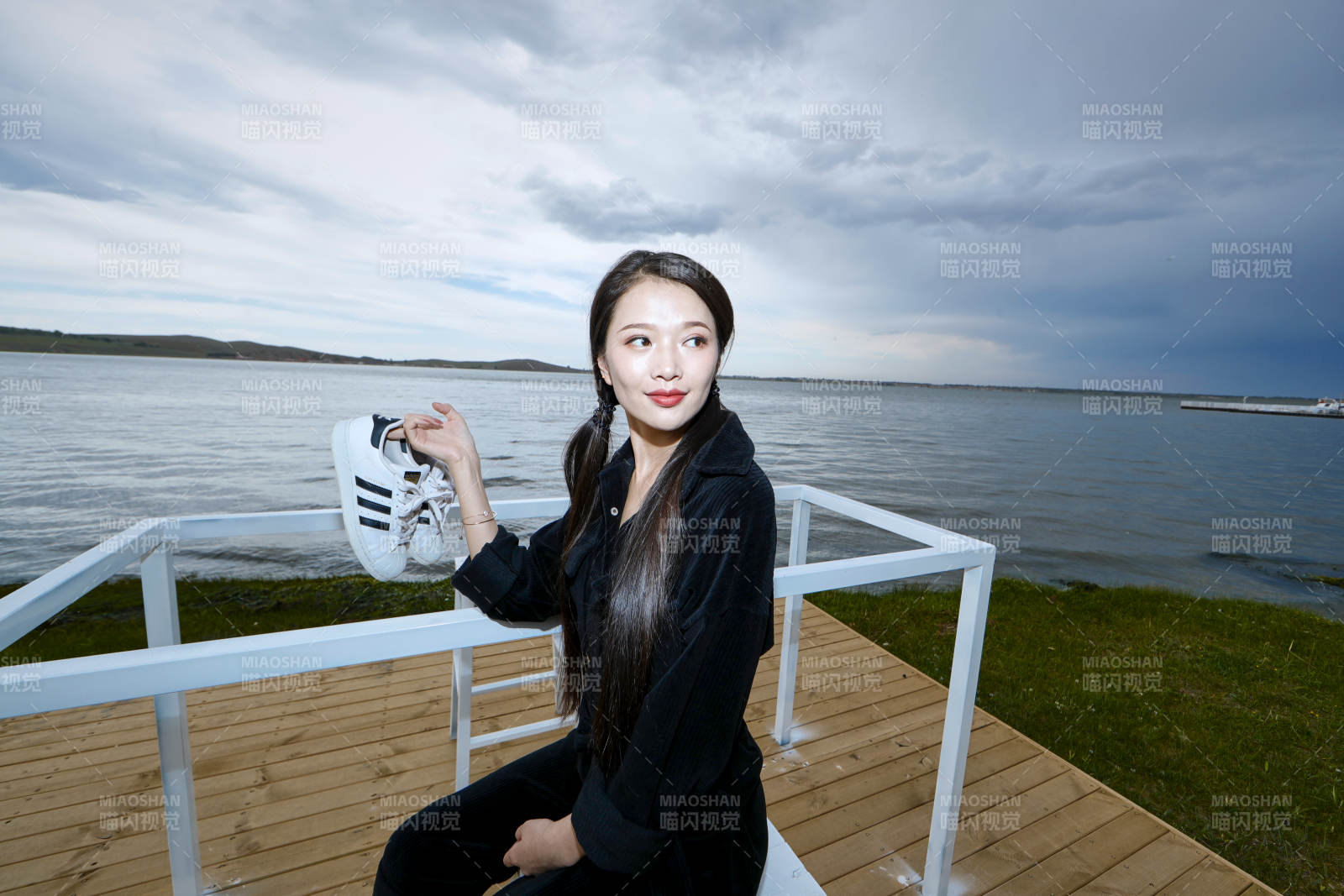 悠閑的坐在美麗湖岸碼頭的長發少女