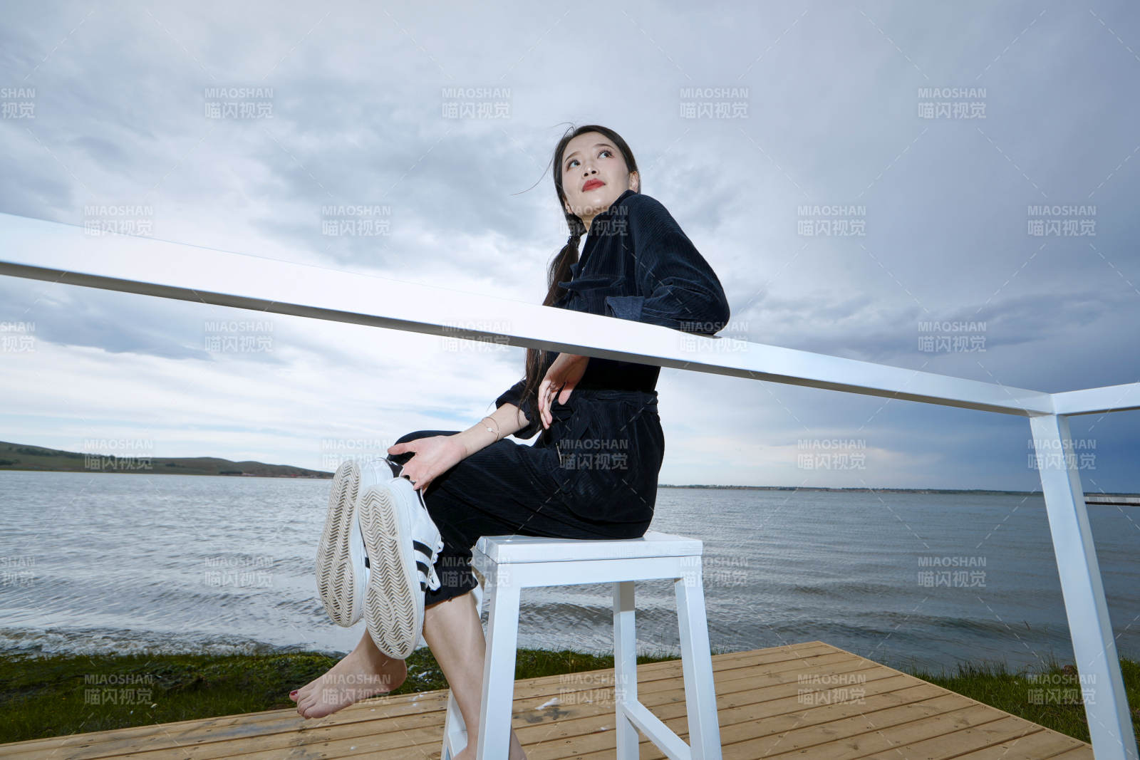 悠閑的坐在美麗湖岸碼頭的長(zhǎng)發(fā)少女