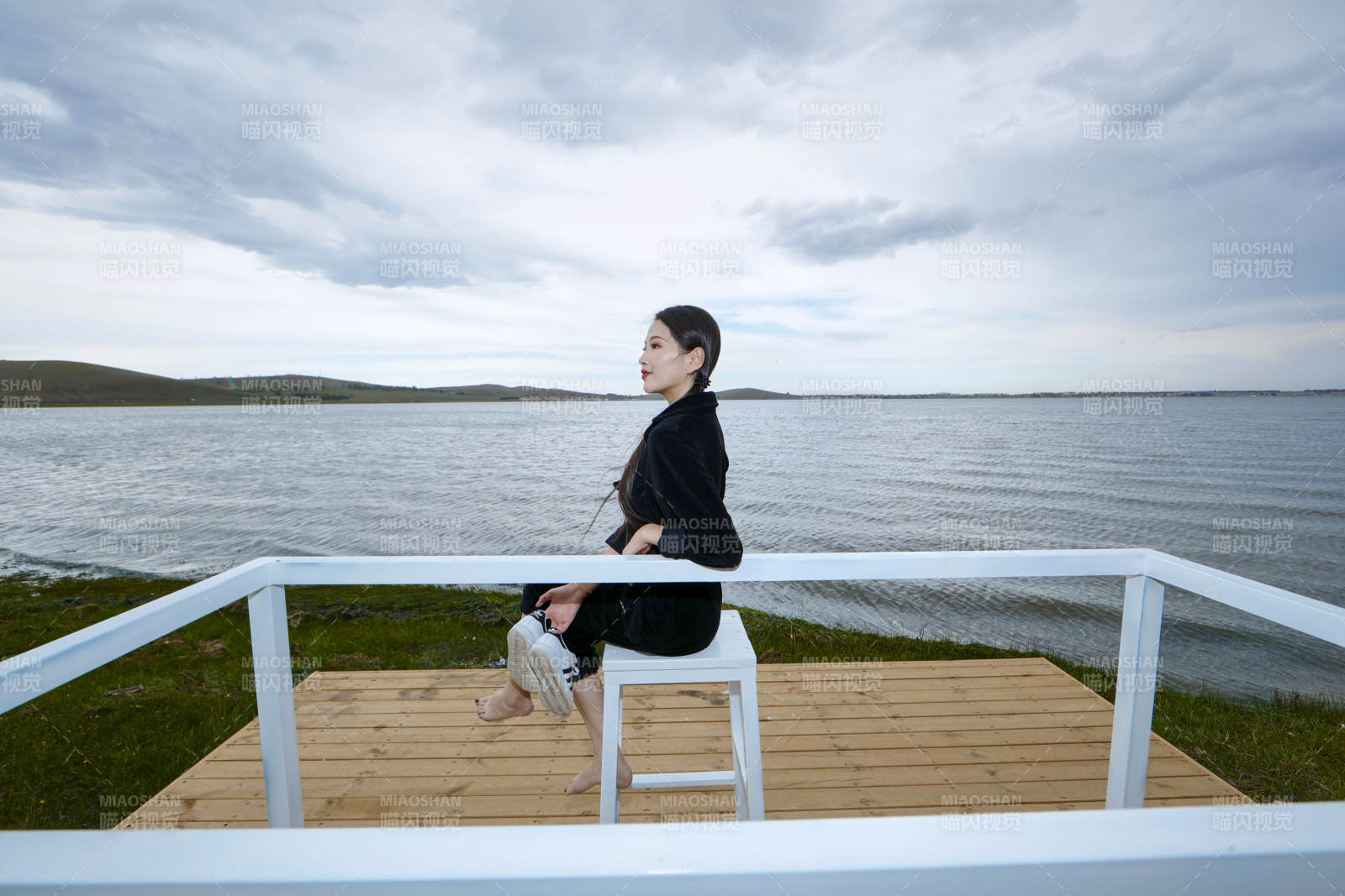 悠閑的坐在美麗湖岸碼頭的長(zhǎng)發(fā)少女