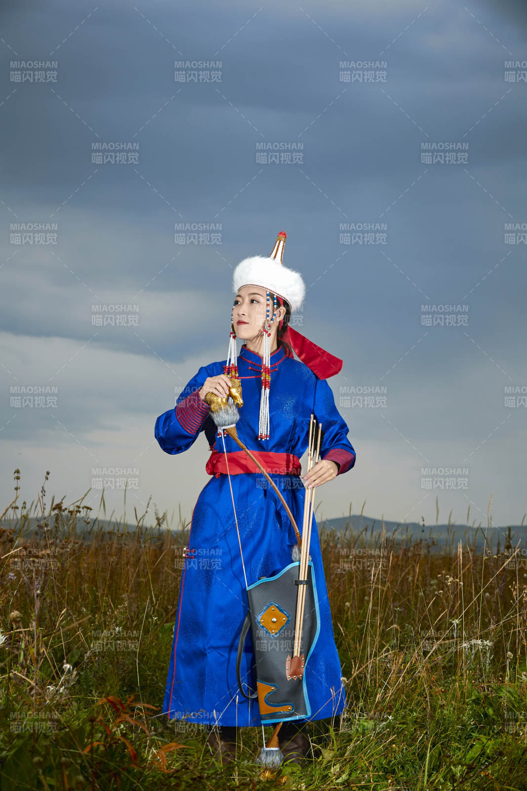 草原湖畔身穿蒙古族飾手持弓箭的蒙族少女