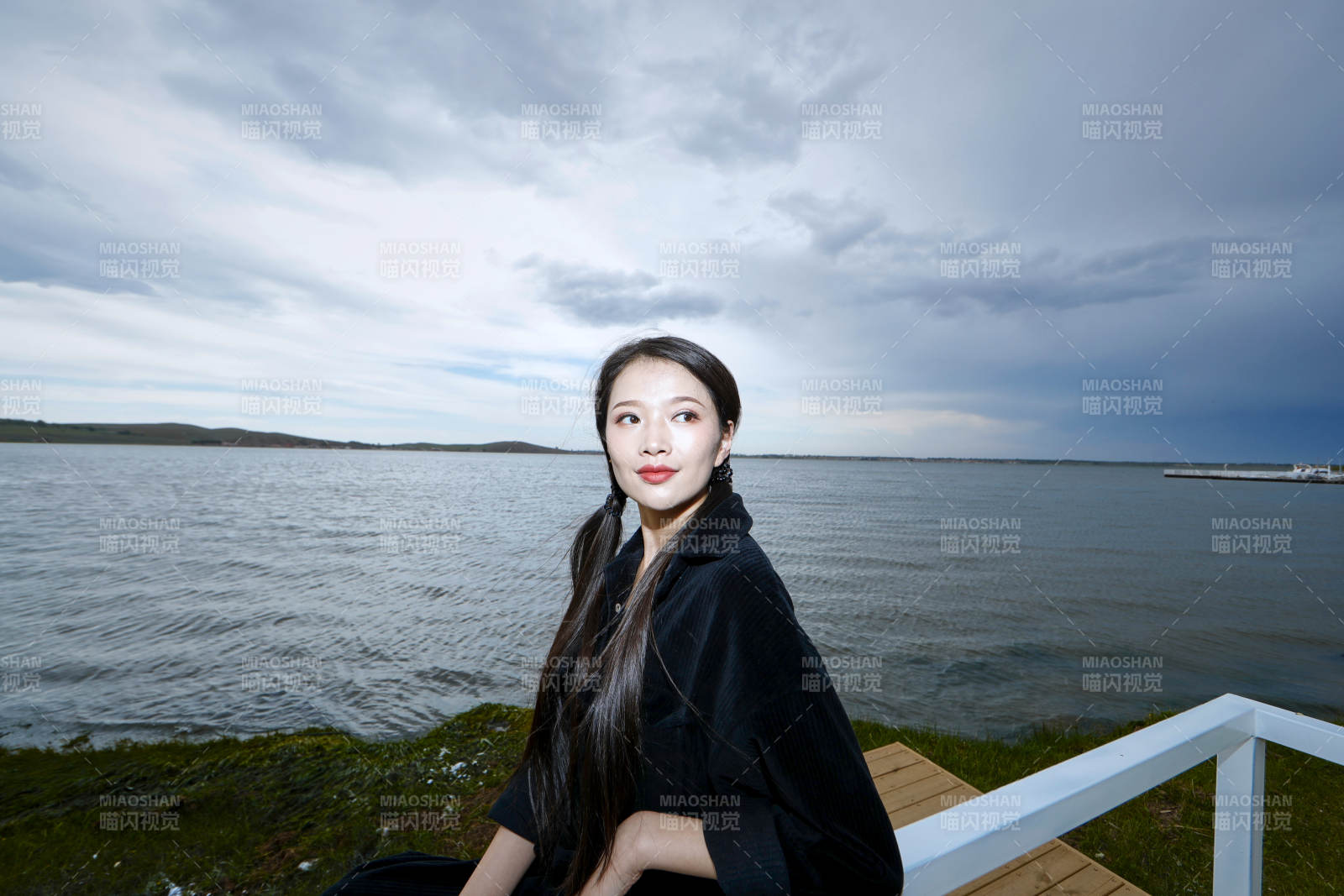 悠閑的坐在美麗湖岸碼頭的長發少女