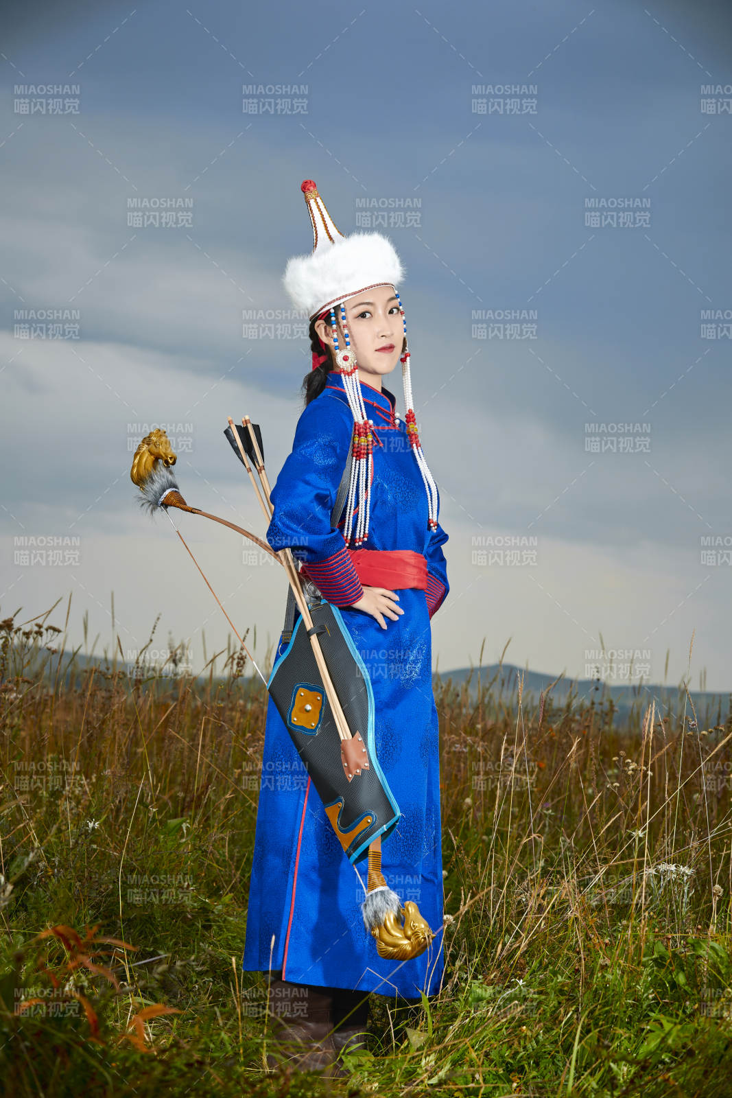 草原湖畔身穿蒙古族飾手持弓箭的蒙族少女