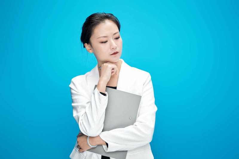 身穿西服拿着手机与文件夹的亚洲商务女士