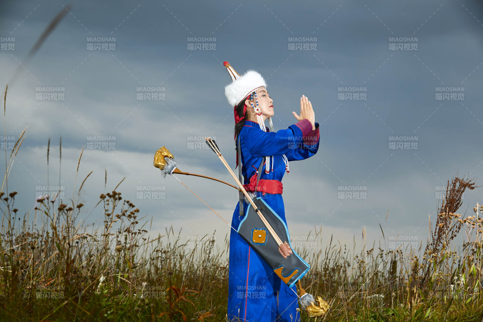 草原湖畔身穿蒙古族饰手持弓箭的蒙族少女