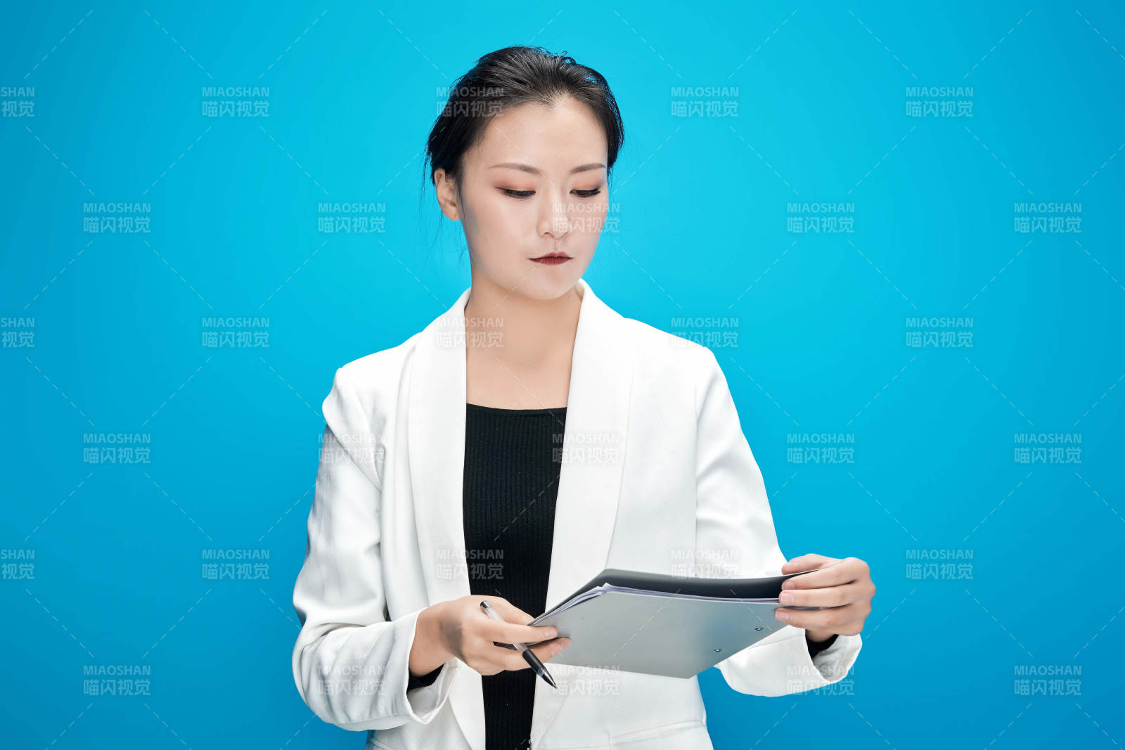 身穿西服拿着手机与文件夹的亚洲商务女士