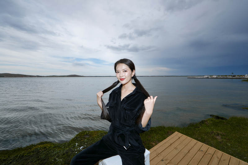 悠闲的坐在美丽湖岸码头的长发少女