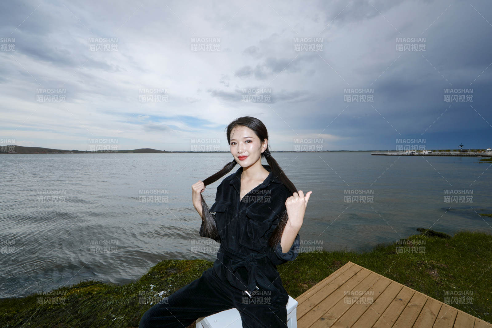 悠闲的坐在美丽湖岸码头的长发少女