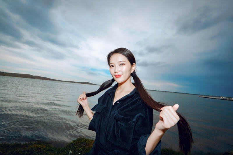 悠闲的坐在美丽湖岸码头的长发少女