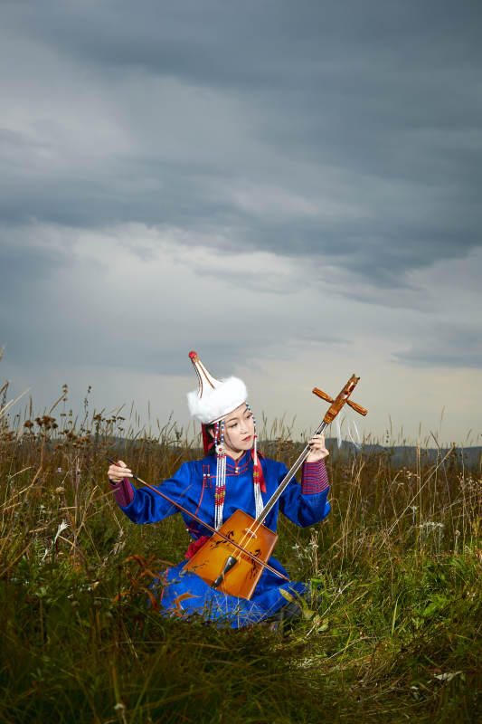 草原上穿蒙古族服饰拉马头琴的蒙族女乐手