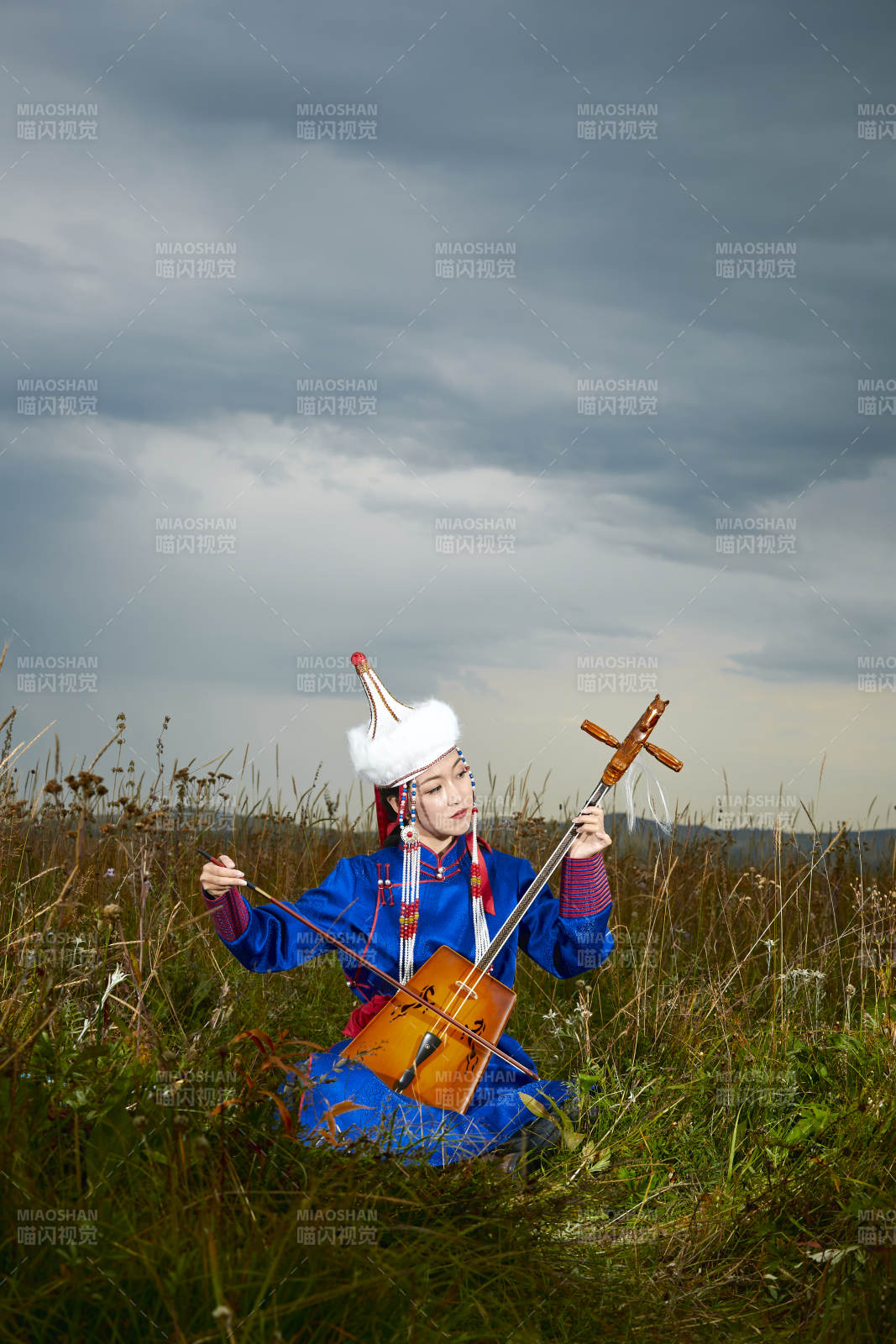 草原上穿蒙古族服饰拉马头琴的蒙族女乐手