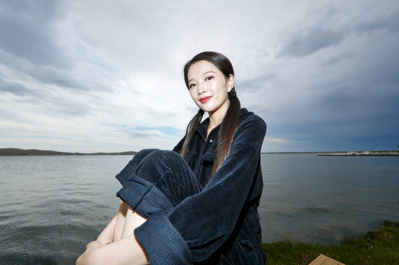 悠闲的坐在美丽湖岸码头的长发少女