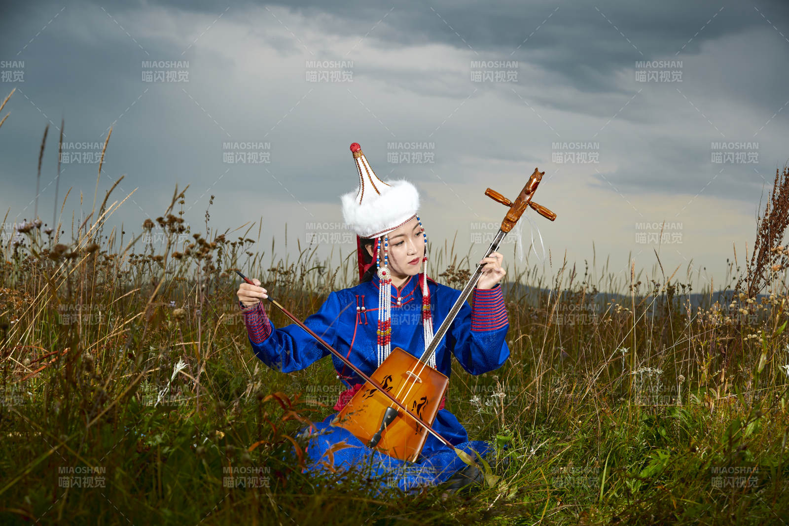 草原上穿蒙古族服饰拉马头琴的蒙族女乐手