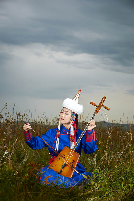草原上穿蒙古族服饰拉马头琴的蒙族女乐手