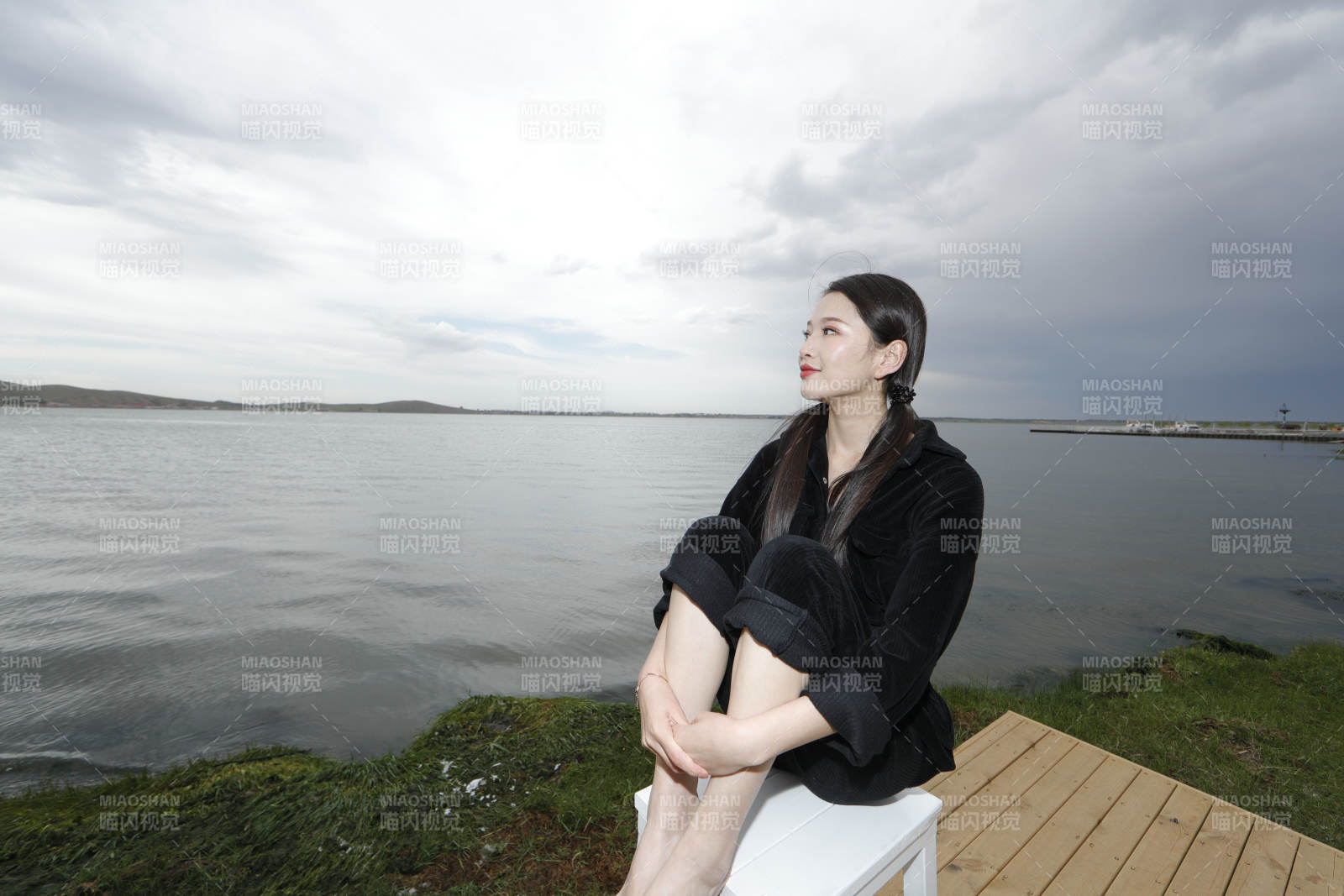 悠閑的坐在美麗湖岸碼頭的長發少女