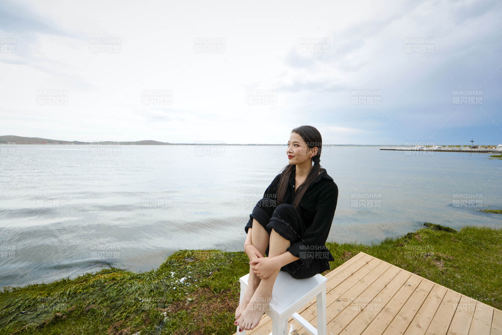 悠閑的坐在美麗湖岸碼頭的長發少女