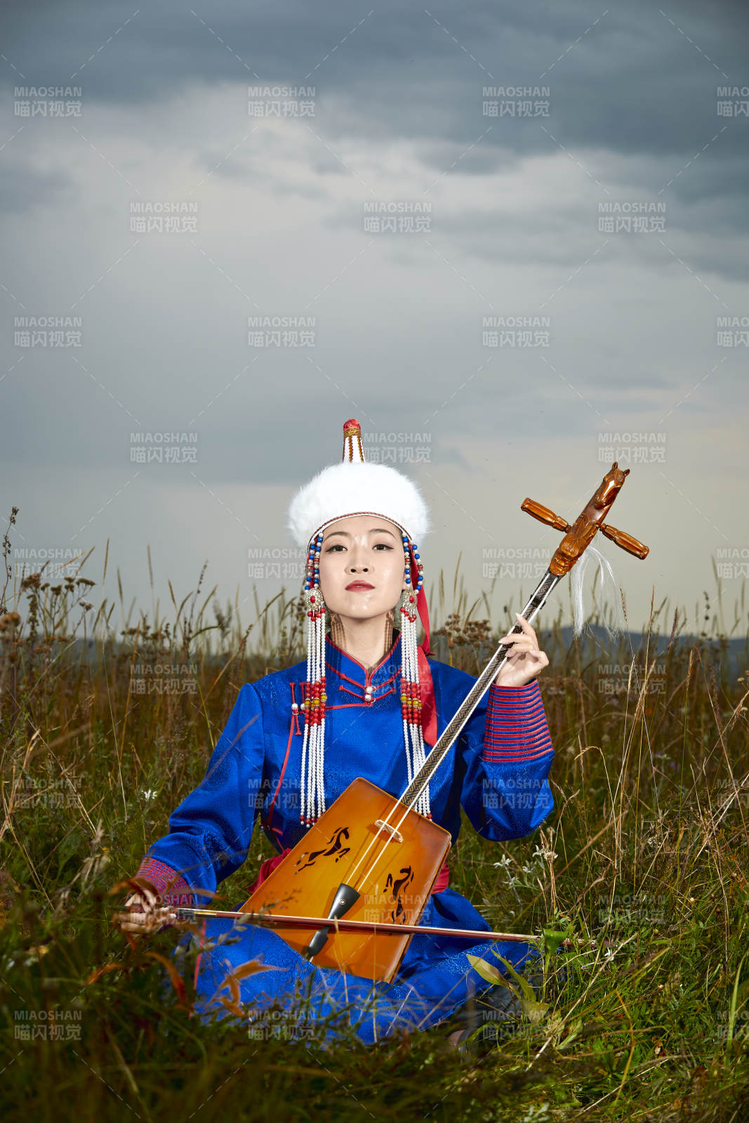 草原上穿蒙古族服饰拉马头琴的蒙族女乐手