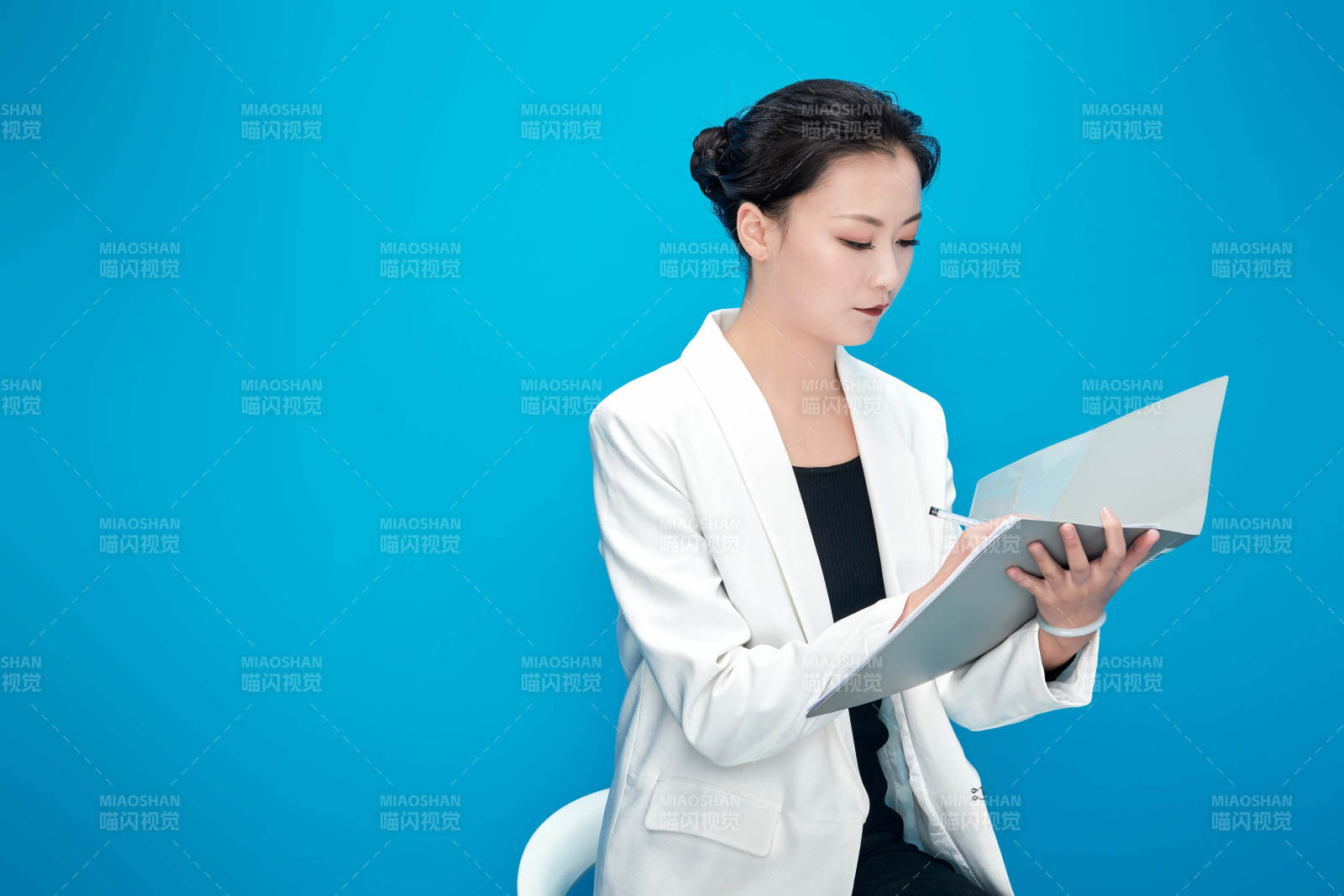 身穿西服拿著手機與文件夾的亞洲商務女士