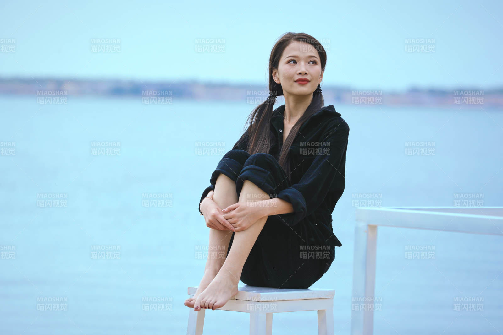 悠閑的坐在美麗湖岸碼頭的亞洲年輕女性人像