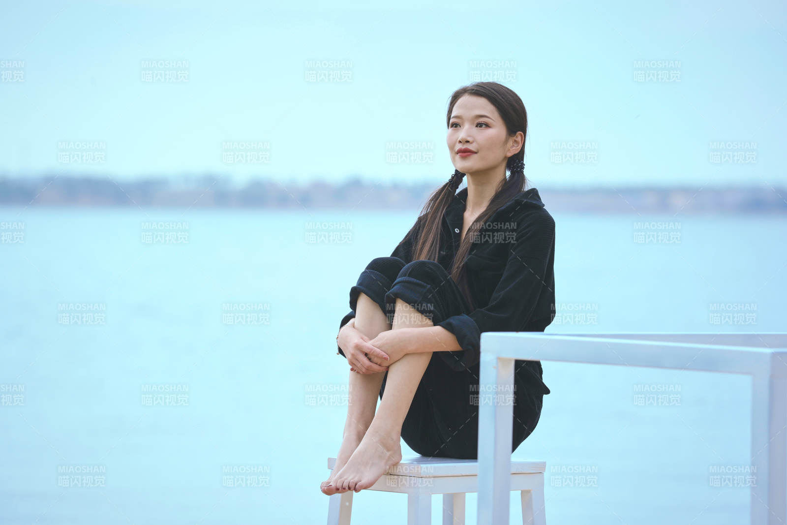 悠閑的坐在美麗湖岸碼頭的亞洲年輕女性人像