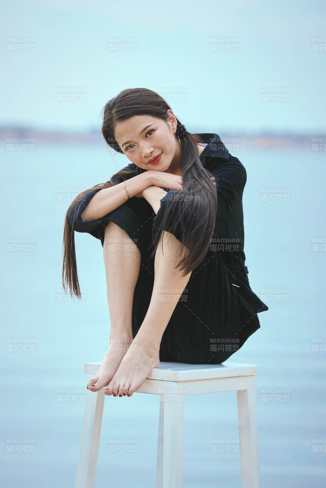 悠閑的坐在美麗湖岸碼頭的亞洲年輕女性人像