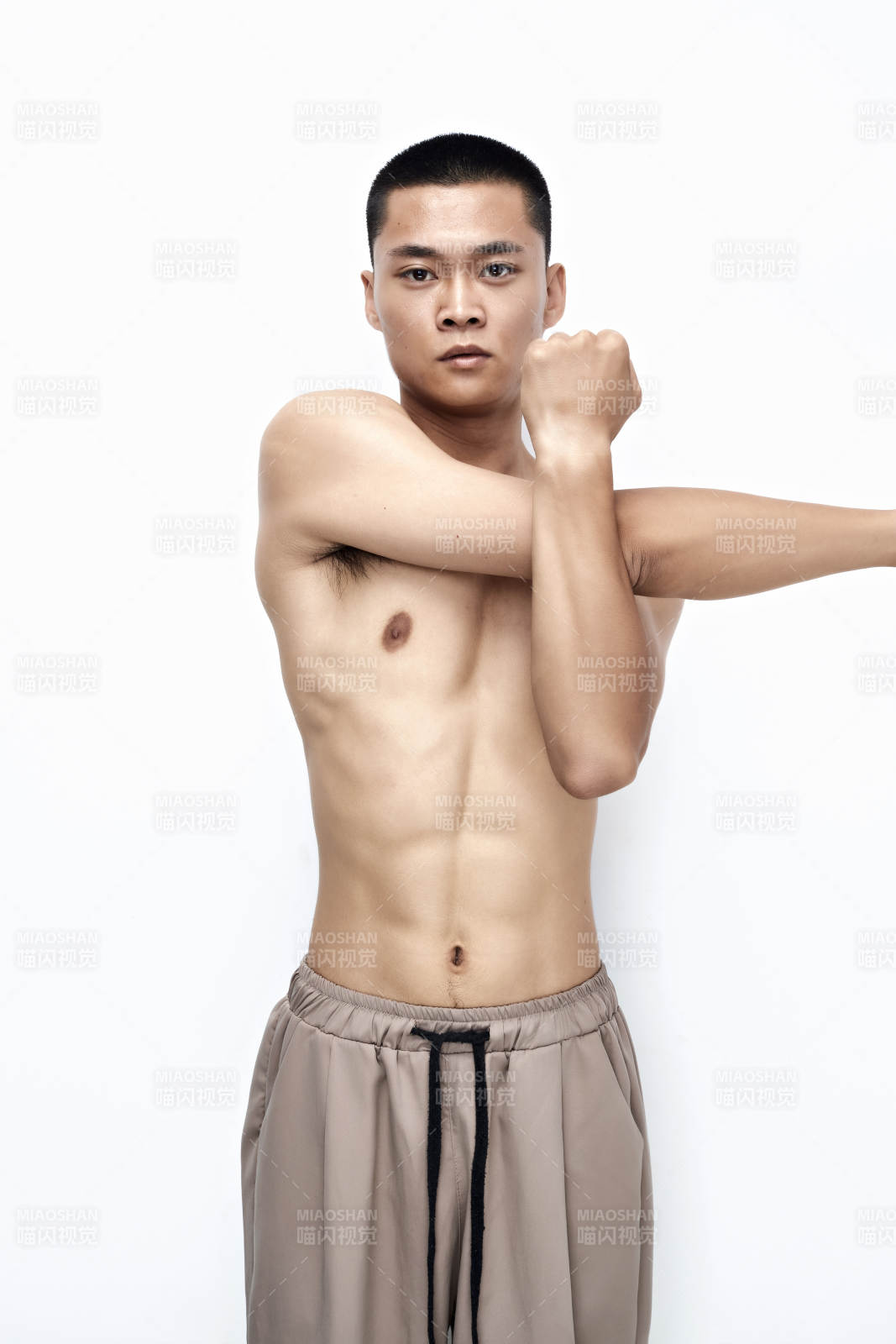 白色背景下展示健身預備拉伸動作的亞洲男性