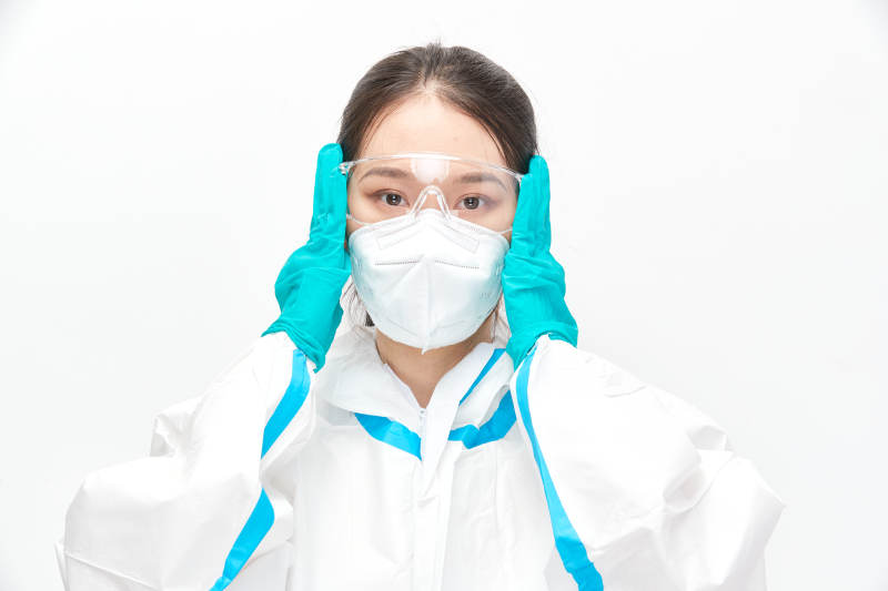 穿白色防護服佩戴護目鏡口罩的女性醫(yī)療人員