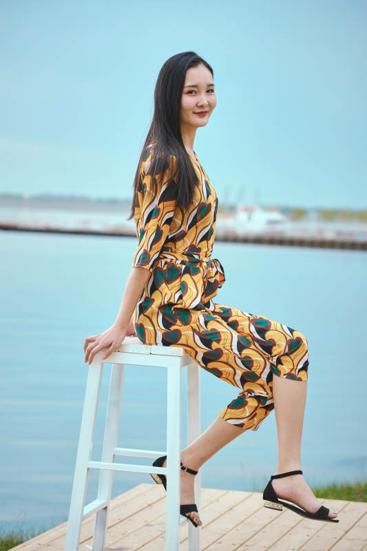 悠闲的坐在美丽湖岸码头的亚洲年轻女性人像