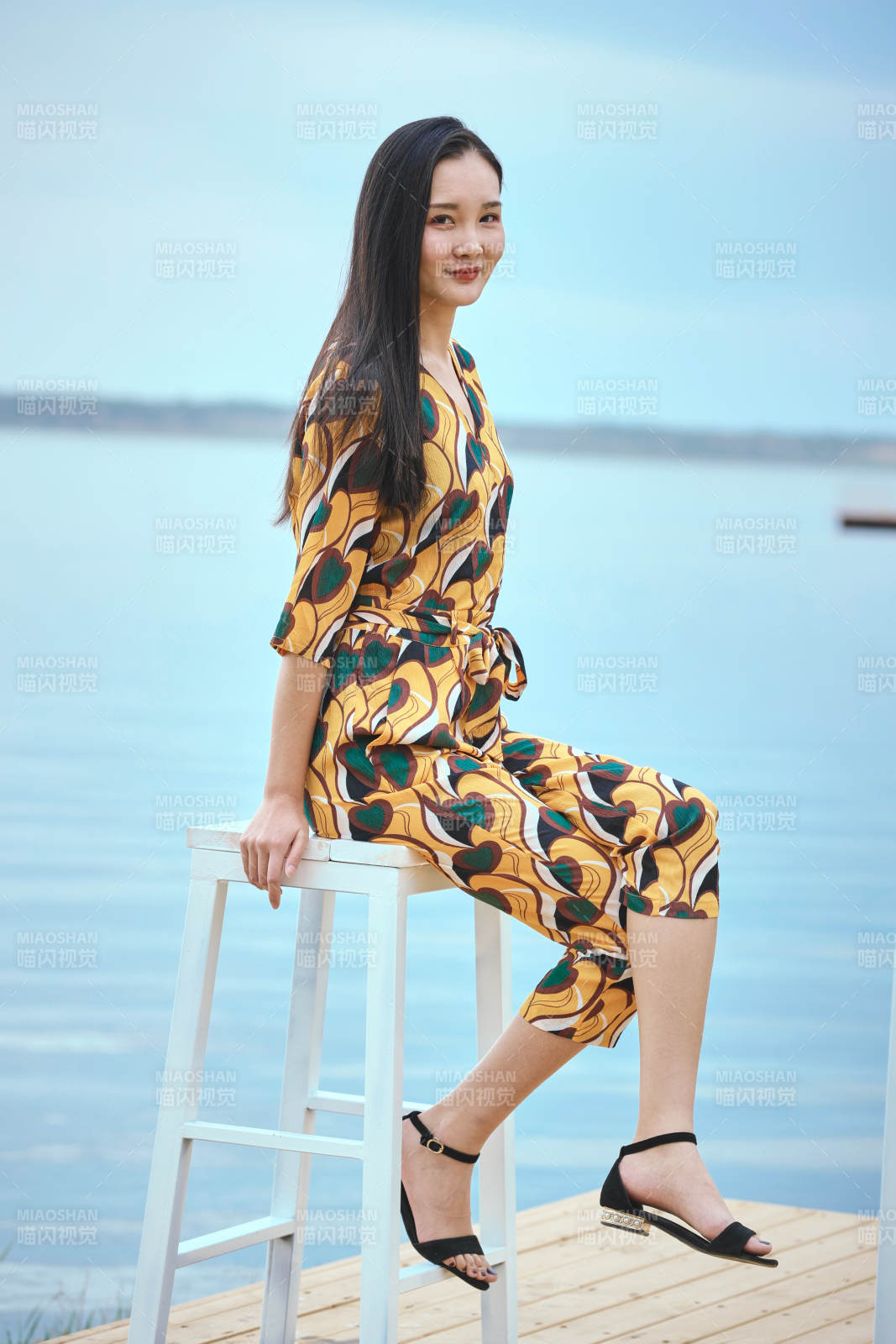 悠閑的坐在美麗湖岸碼頭的亞洲年輕女性人像