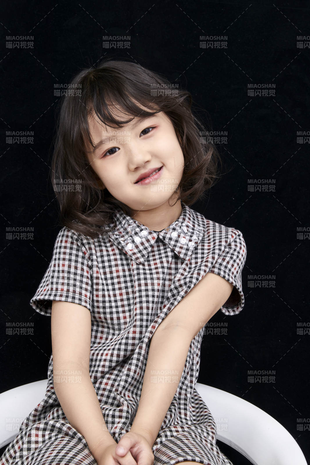黑色背景里坐在凳子上的可愛的亞洲小女孩兒童